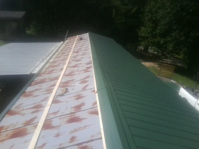 Old rusted panels beside newly installed green metal roofing — Wind Damage Roof Repair by Roofing Brothers in Blanding