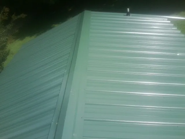 New green metal panels meeting at the ridge of a roof — Flat Roof Repair work by our crew in Blanding