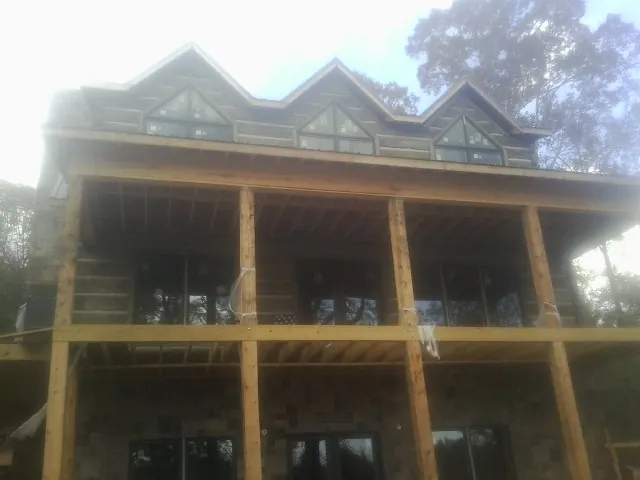 Dormers and porch framing on a large log home under construction — Roof Coating work by our crew in Blanding