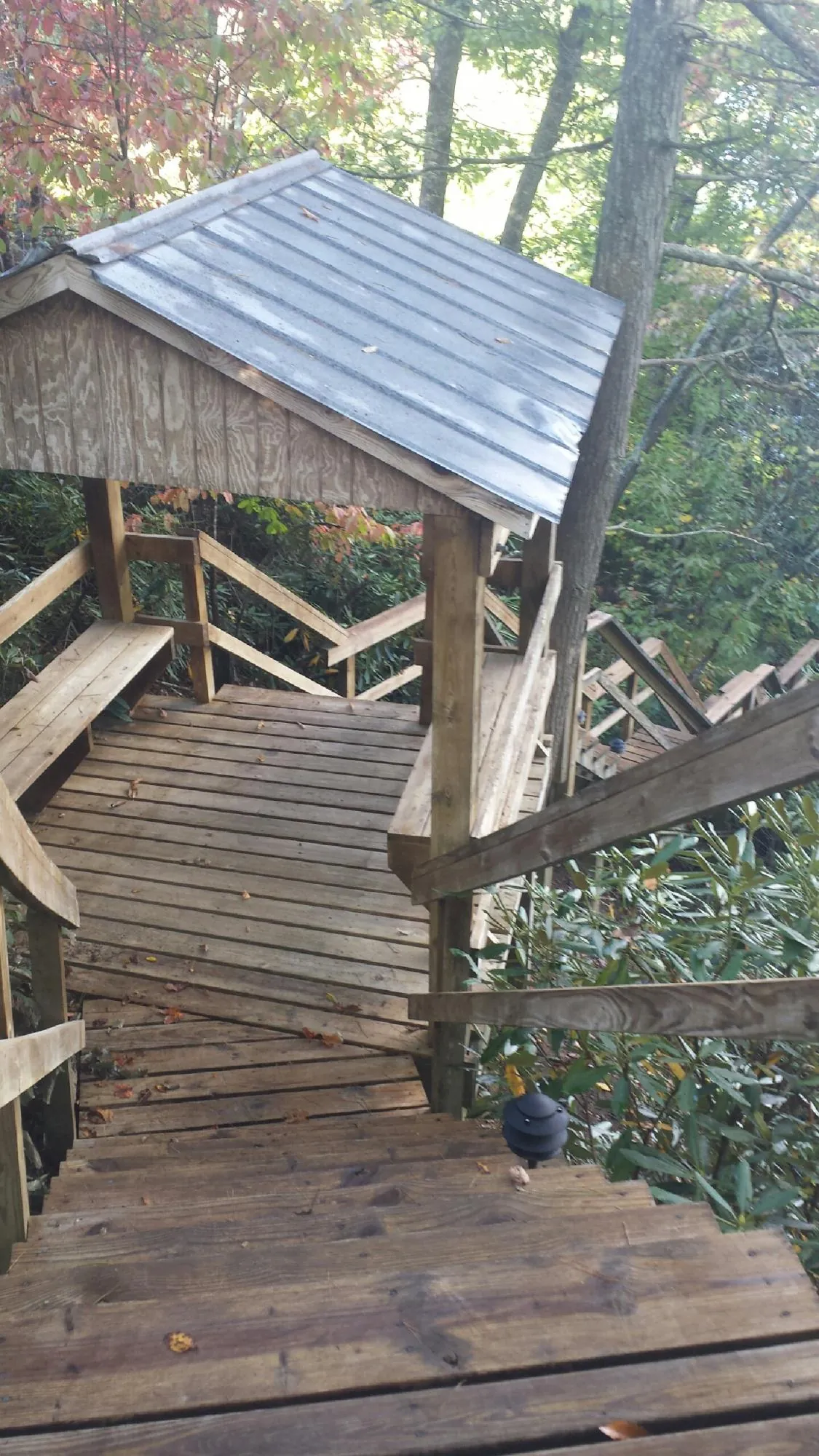 Metal roofed shelter over wooden steps on a wooded walkway — Skylight Repair & Installation work by our crew in Blanding