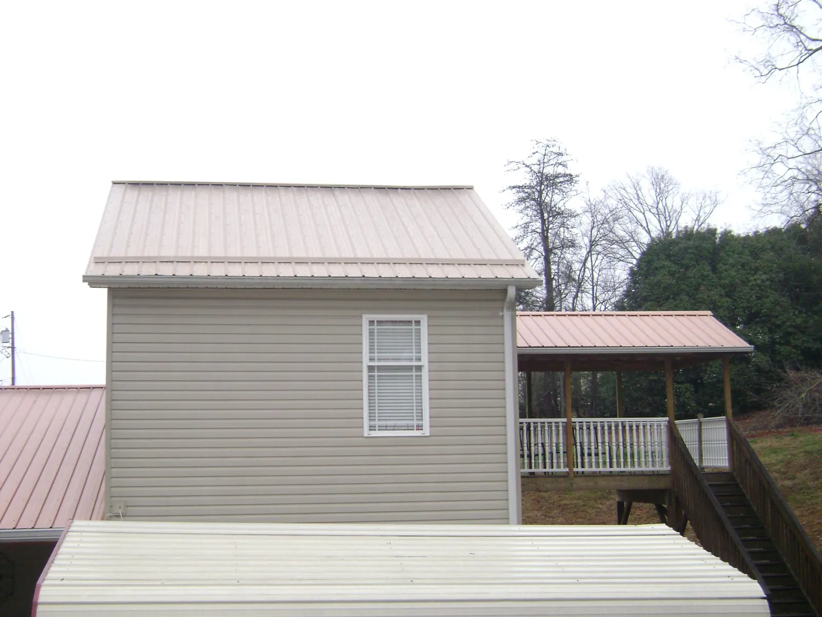 Tan metal roofs on a two story addition and attached porch, from a Roof Replacement job in Blanding