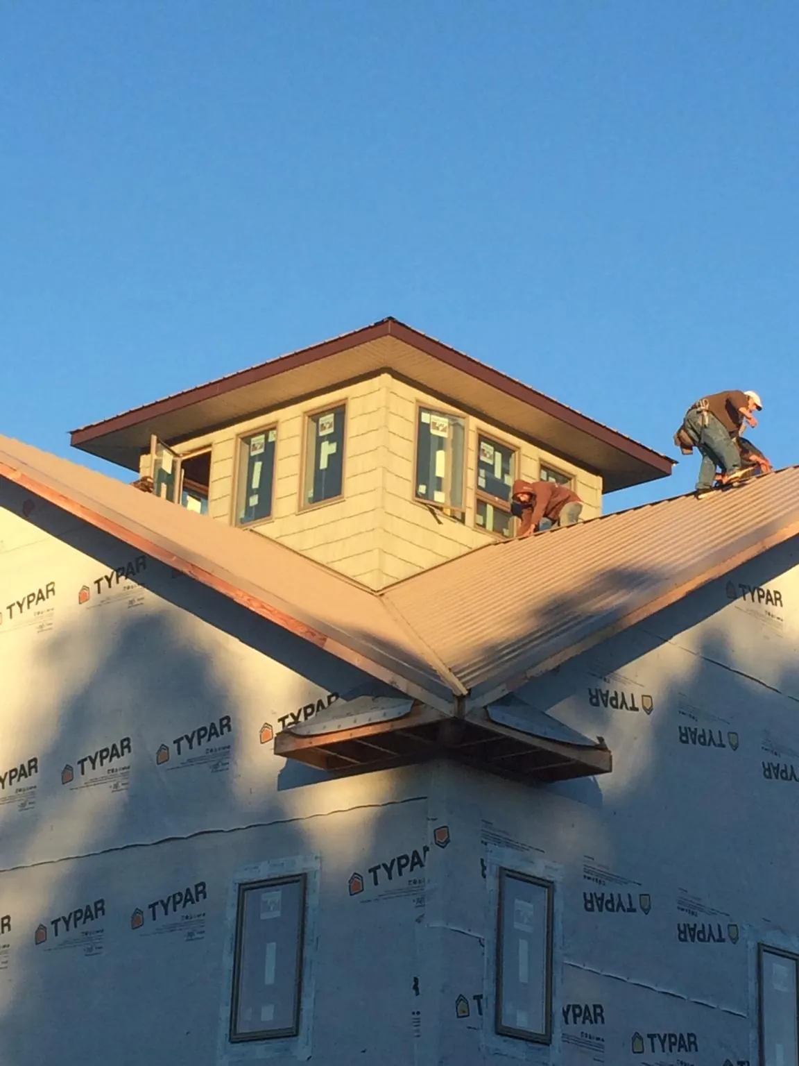 Roofers working around a rooftop cupola on a new metal roof at sunset — Roof Waterproofing in Blanding by Roofing Brothers